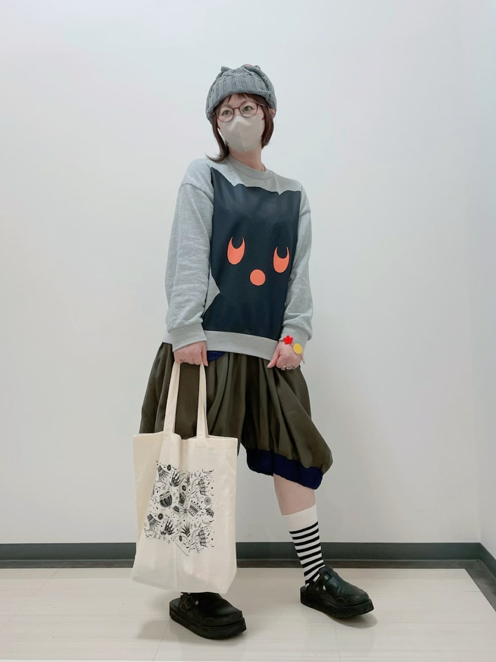 グレー系のスウェット、グリーン系のパンツ、ホワイト系のトートバッグを着用したレディースの春コーディネートの1枚目の写真