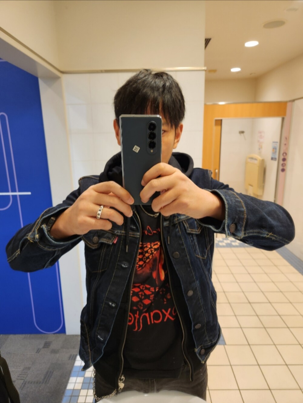ブルー系のデニムジャケット、ブラック系のパーカー、ブラック系のTシャツ/カットソーを着用したメンズの秋コーディネートの2枚目の写真