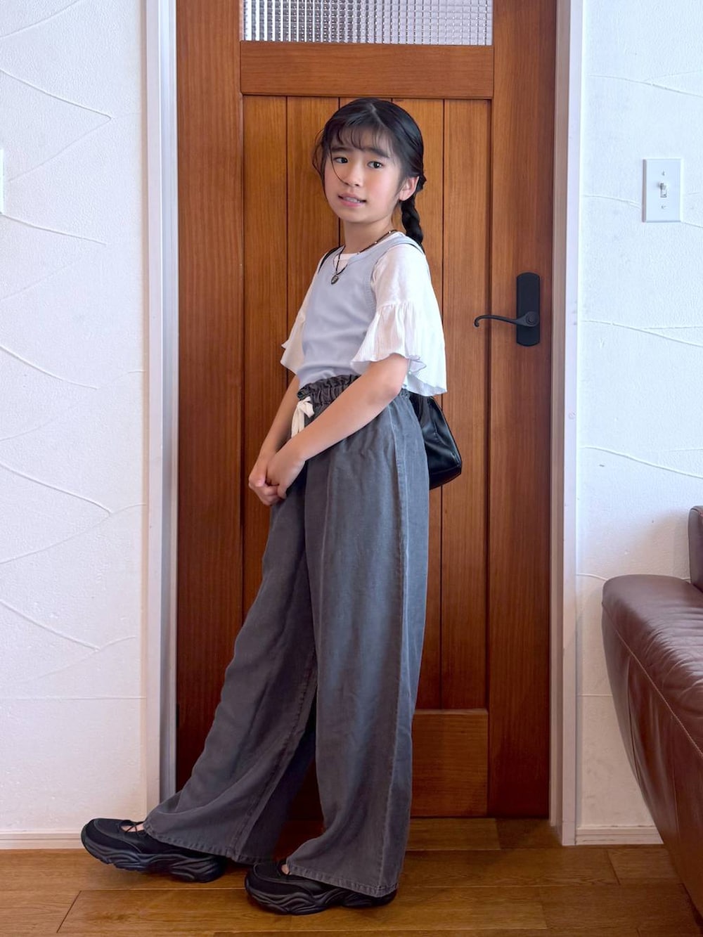 ブラウン系のその他パンツ、ブラック系のショルダーバッグ、ブラック系のスニーカーを着用したキッズの春コーディネートの7枚目の写真