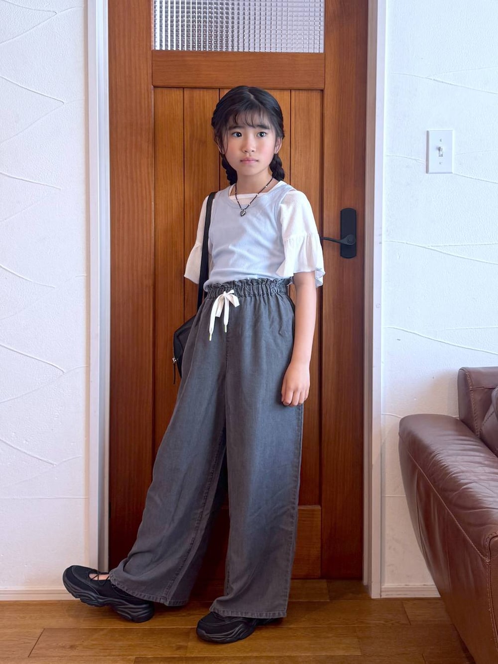 ブラウン系のその他パンツ、ブラック系のショルダーバッグ、ブラック系のスニーカーを着用したキッズの春コーディネートの4枚目の写真