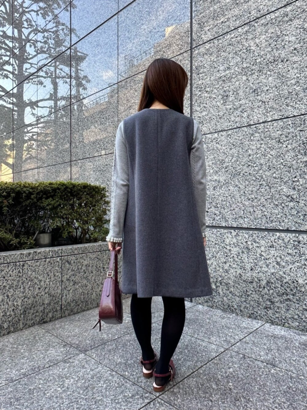 グレー系のジャンパースカート、グレー系のニット/セーター、レッド系のサンダルを着用したレディースの冬コーディネートの3枚目の写真