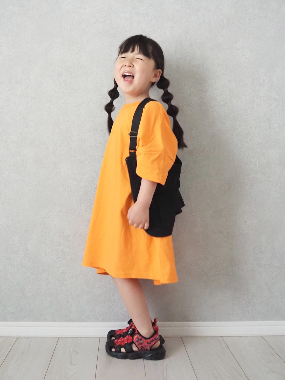 レッド系のサンダル、オレンジ系のワンピースを着用したキッズの夏コーディネートの3枚目の写真