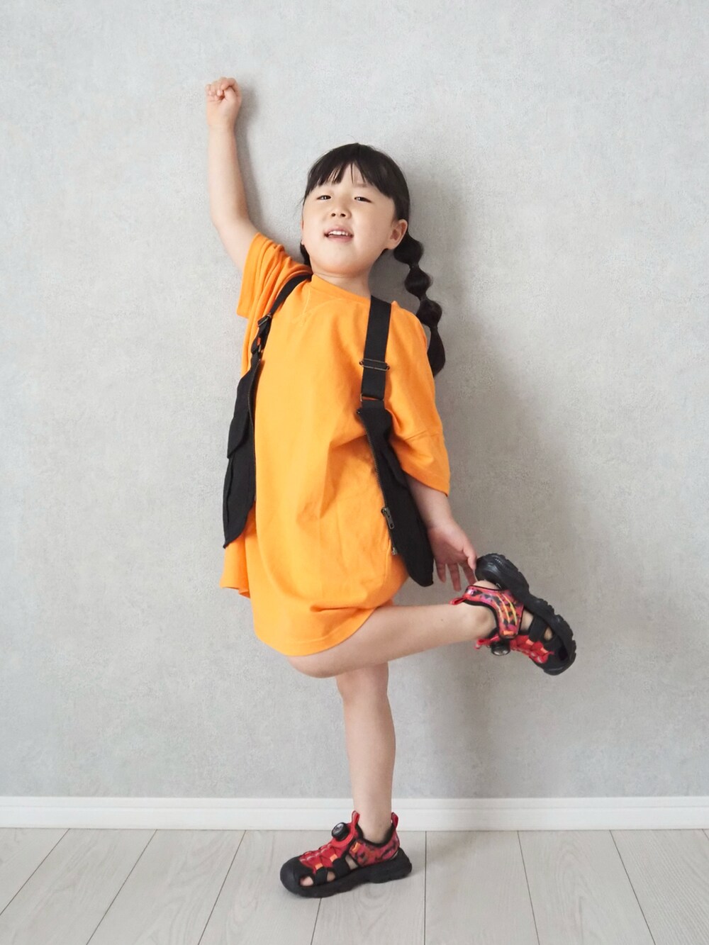 レッド系のサンダル、オレンジ系のワンピースを着用したキッズの夏コーディネートの2枚目の写真