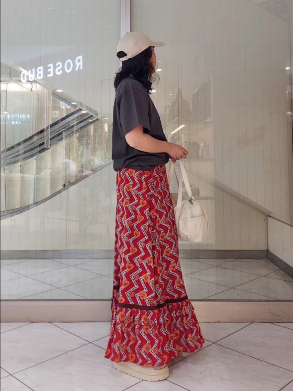 レッド系のスカート、グレー系のTシャツ/カットソー、ホワイト系のボストンバッグを着用したレディースの春コーディネートの2枚目の写真