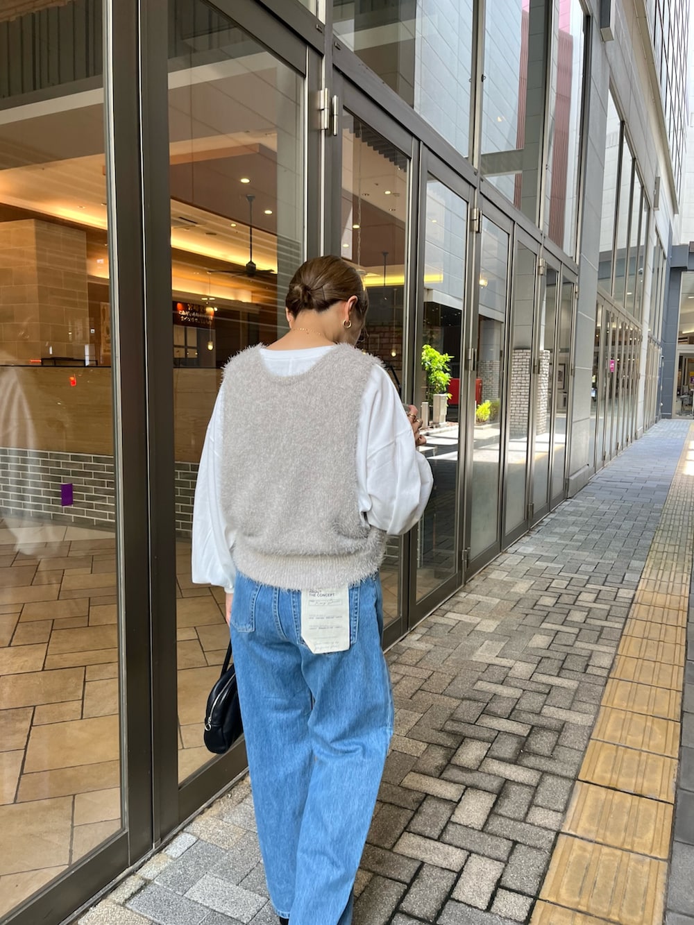 グレー系のベスト、ホワイト系のTシャツ/カットソー、ブルー系のデニムパンツを着用したレディースの秋コーディネートの5枚目の写真
