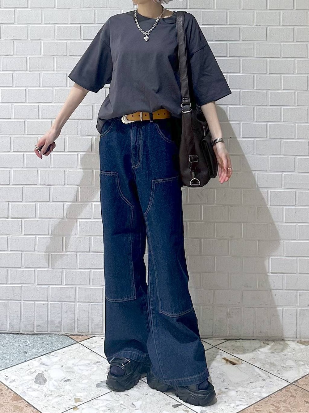 ブラウン系のショルダーバッグ、ブルー系のデニムパンツ、グレー系のTシャツ/カットソーを着用したレディースの春コーディネートの3枚目の写真