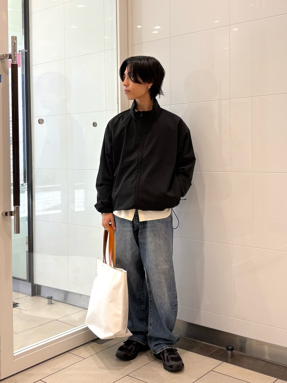 ブラック系のナイロンジャケット、ベージュ系のシャツ/ブラウス、ブルー系のデニムパンツを着用したメンズの夏コーディネートの5枚目の写真