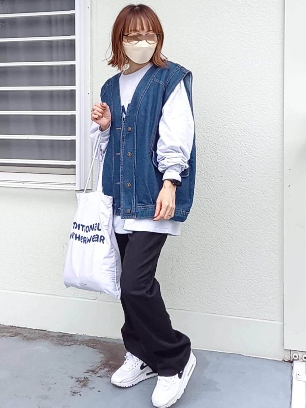 ブラック系のスラックス、ブルー系のベスト、ベージュ系のTシャツ/カットソーを着用したレディースの秋コーディネートの2枚目の写真