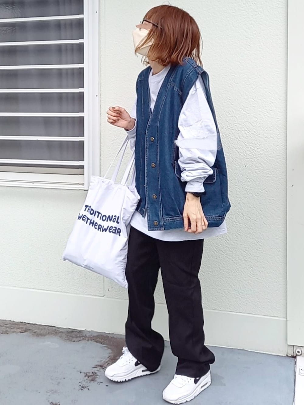 ブラック系のスラックス、ブルー系のベスト、ベージュ系のTシャツ/カットソーを着用したレディースの秋コーディネートの3枚目の写真