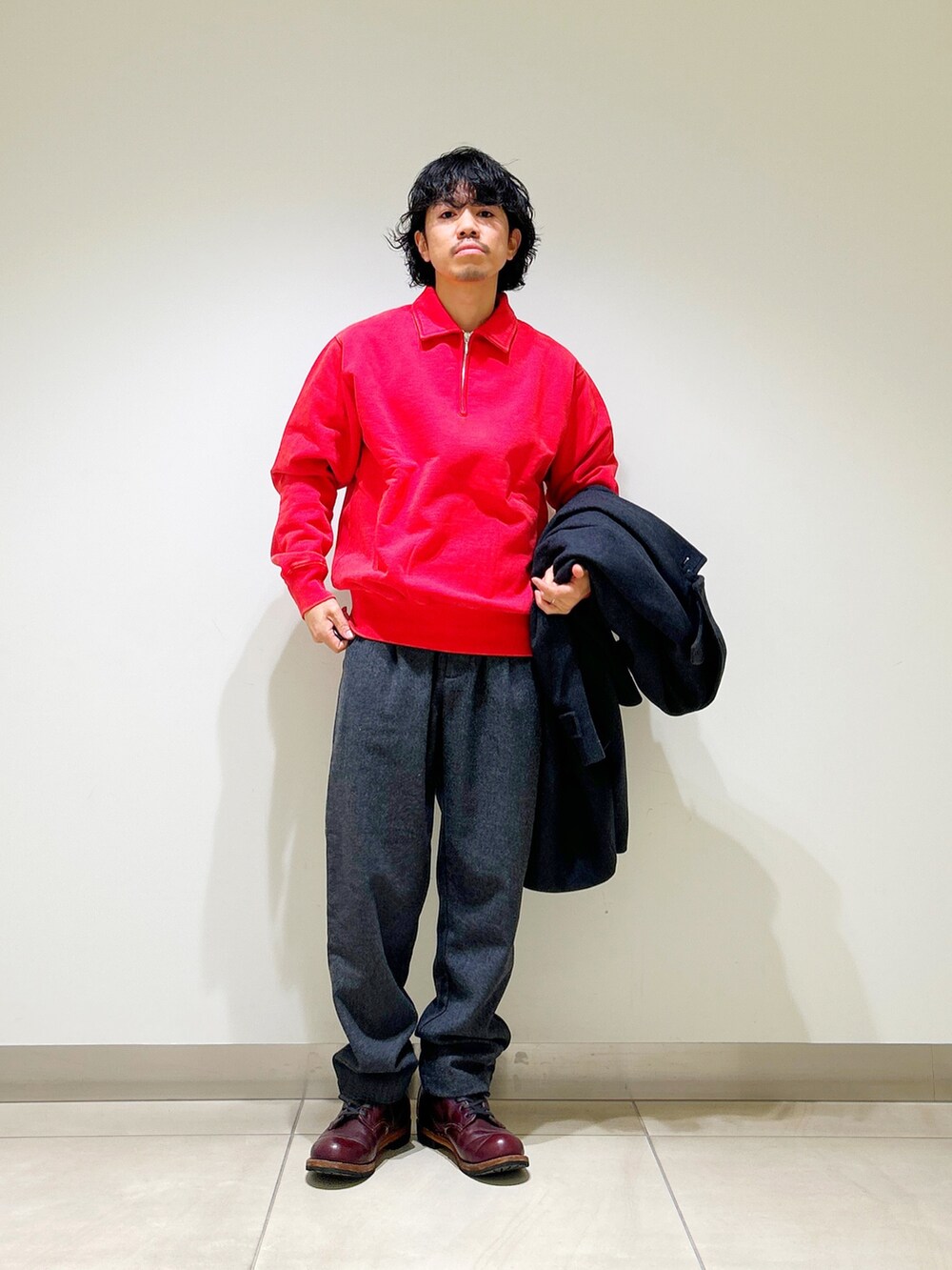 グレー系のステンカラーコート、レッド系のスウェット、グレー系のその他パンツを着用したメンズの冬コーディネートの2枚目の写真