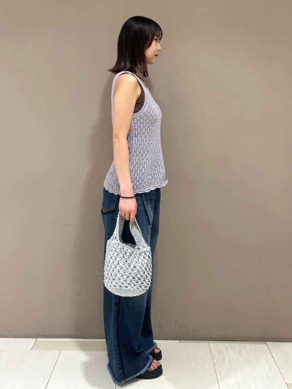 ブルー系のデニムパンツ、パープル系のタンクトップ、ブラウン系のTシャツ/カットソーを着用したレディースの春コーディネートの2枚目の写真
