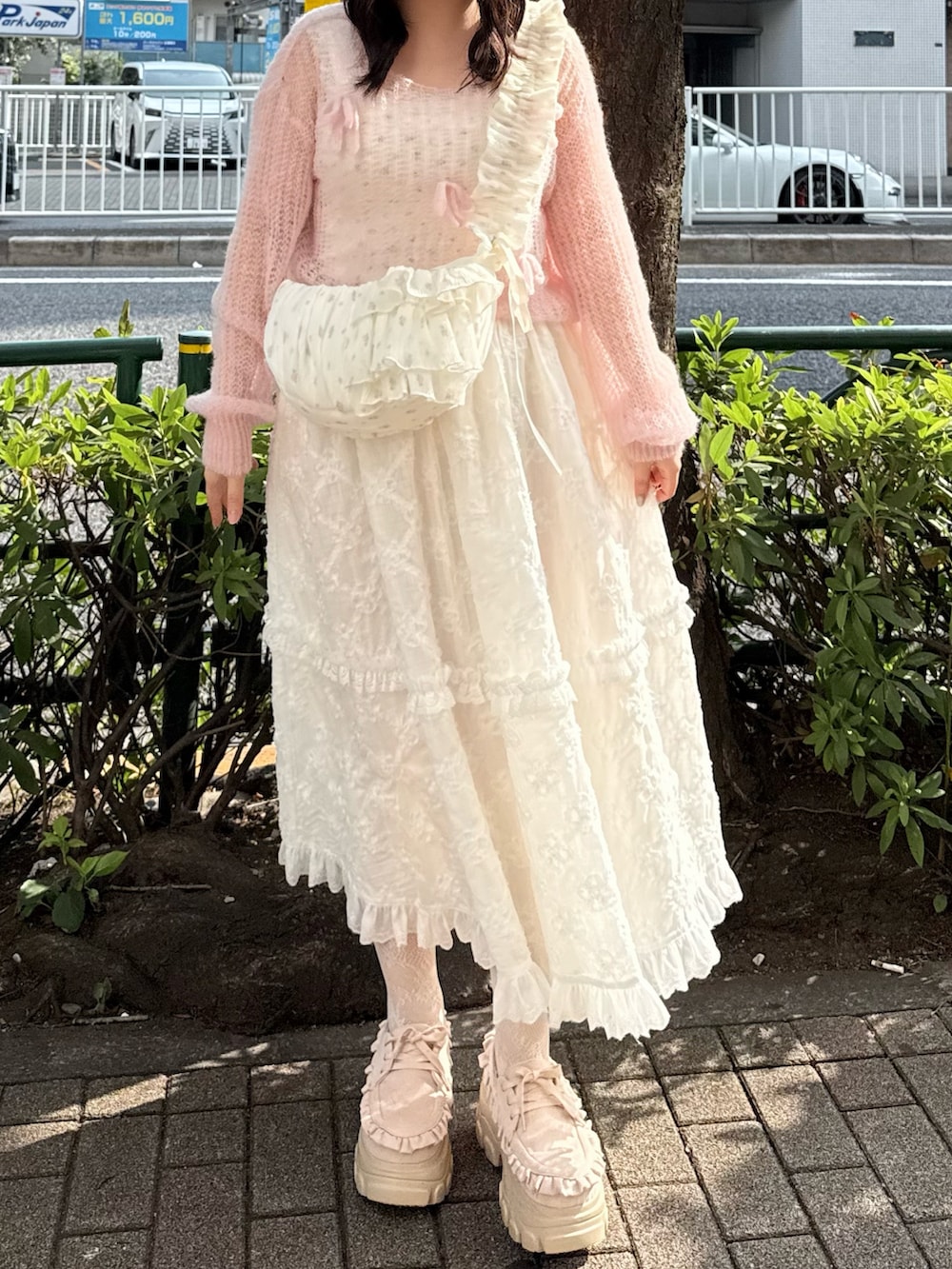 ピンク系のローファー、ホワイト系のスカート、ホワイト系のショルダーバッグを着用したレディースの夏コーディネートの2枚目の写真