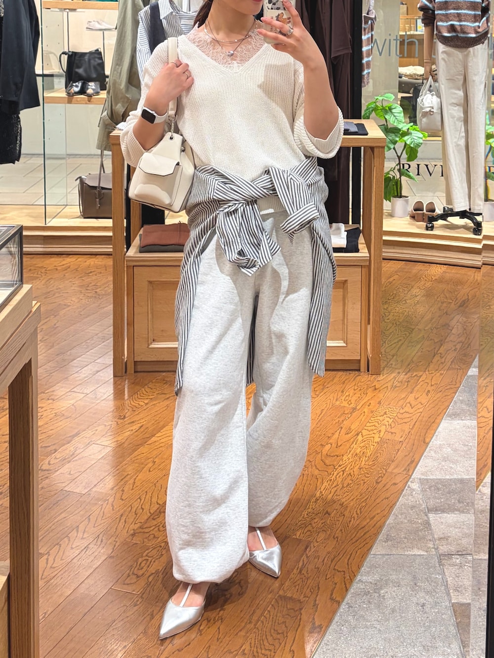グレー系のスウェットパンツ、シルバー系のその他シューズ、ホワイト系のニット/セーターを着用したレディースの春コーディネートの2枚目の写真