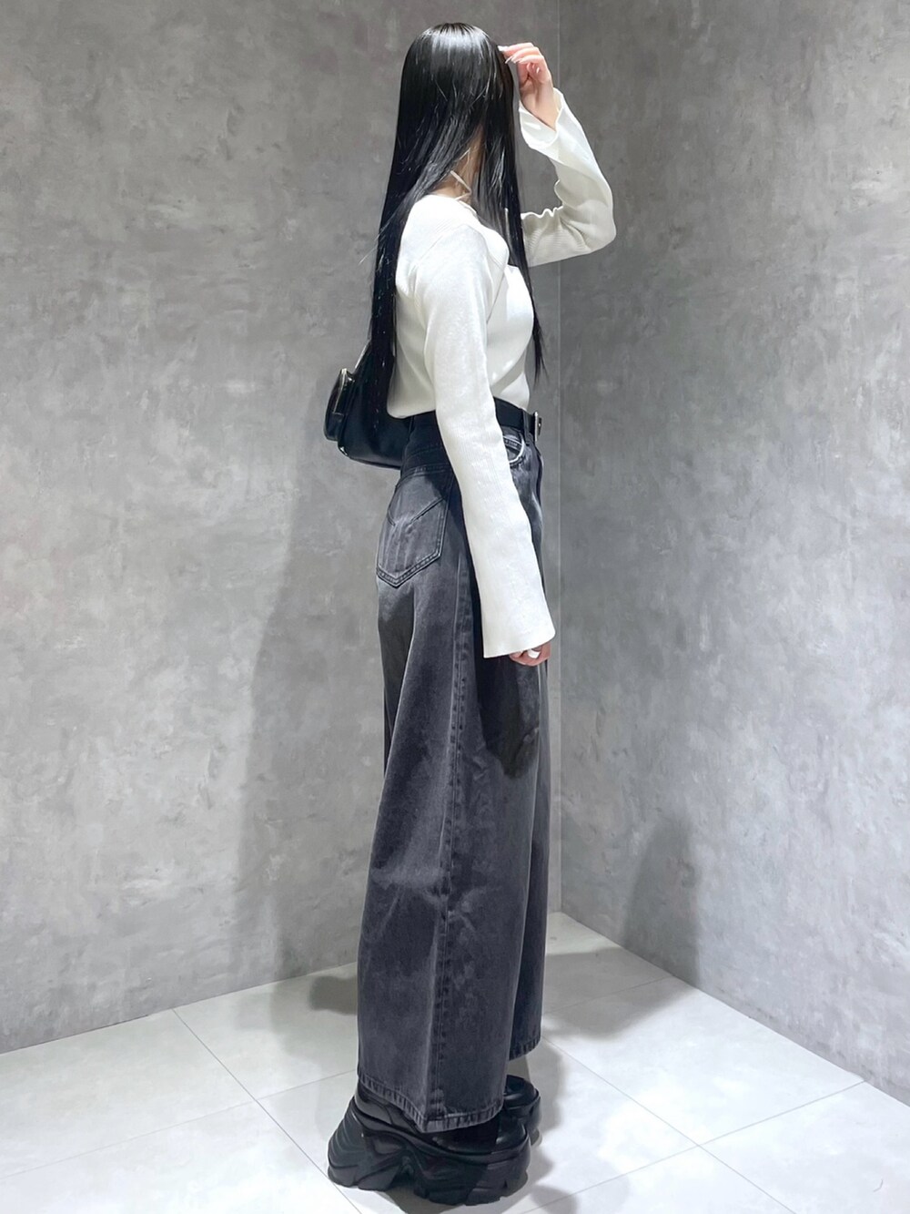 ホワイト系のニット/セーター、ブラック系のデニムパンツ、ブラック系のスニーカーを着用したレディースの冬コーディネートの5枚目の写真