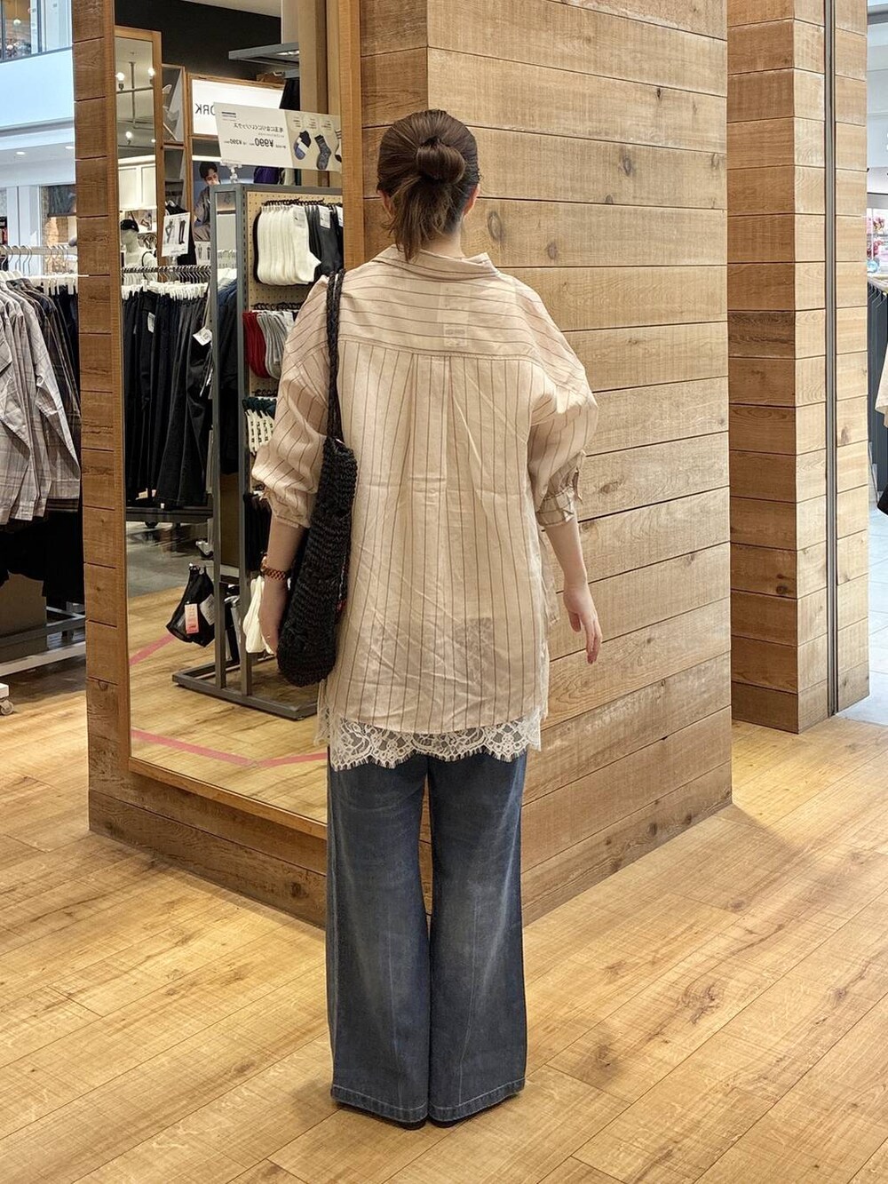 ブルー系のデニムパンツ、ベージュ系のシャツ/ブラウス、ブラック系のトートバッグを着用したレディースの春コーディネートの3枚目の写真