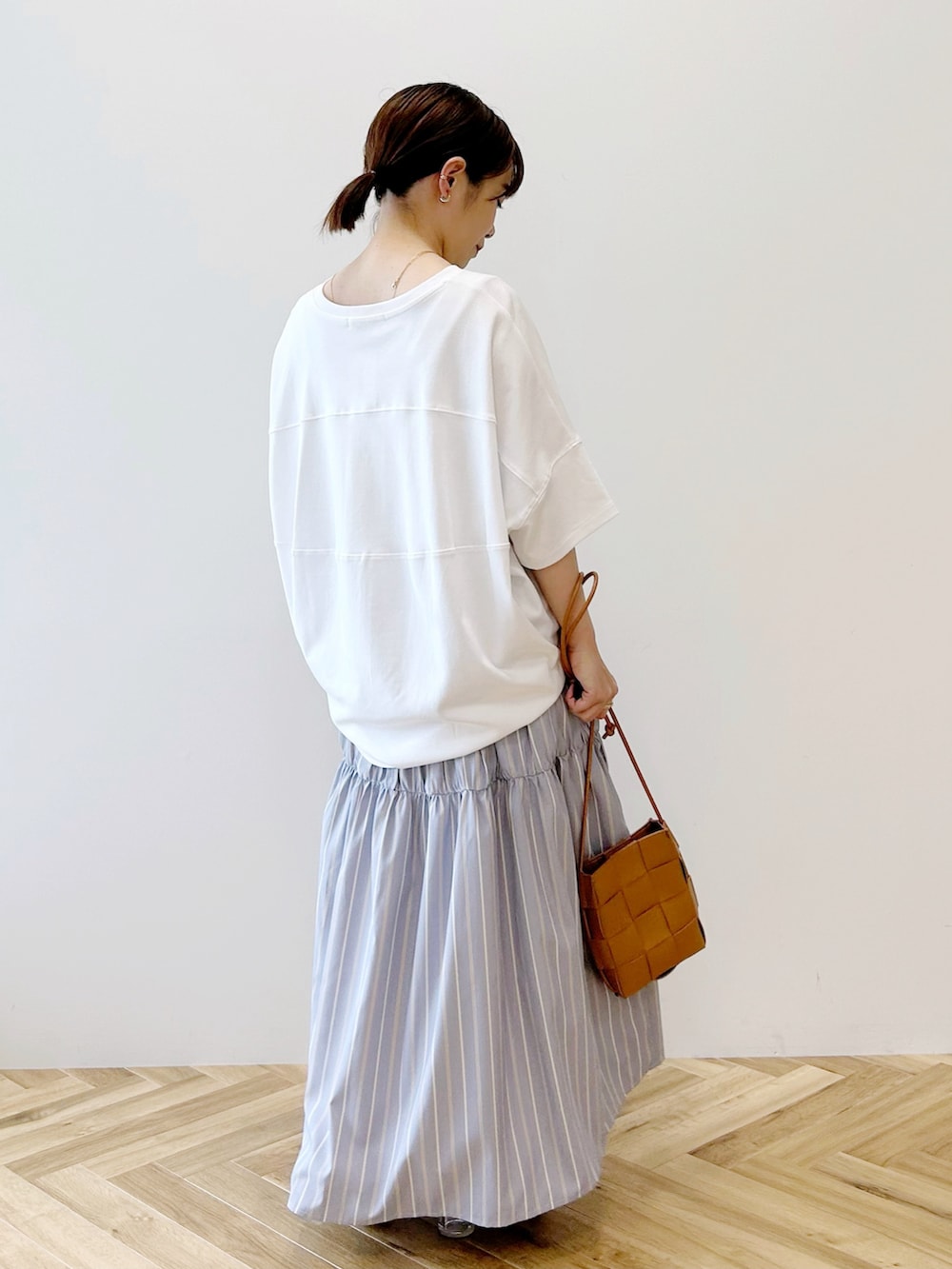 ブルー系のスカート、イエロー系のショルダーバッグ、ホワイト系のTシャツ/カットソーを着用したレディースの春コーディネートの3枚目の写真