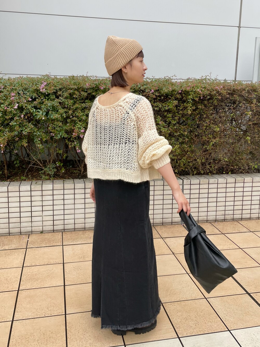 ブラック系のジャンパースカート、ホワイト系のニット/セーター、ブラック系のトートバッグを着用したレディースの秋コーディネートの2枚目の写真