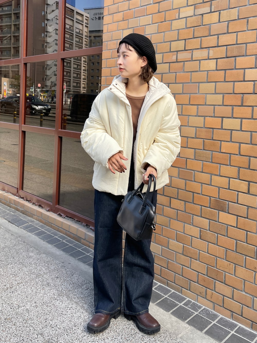 ホワイト系のブルゾン、ブラウン系のTシャツ/カットソー、ブルー系のデニムパンツを着用したレディースの秋コーディネートの2枚目の写真