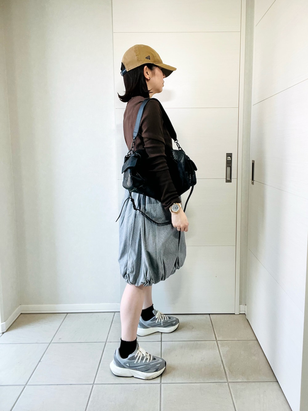 ブラウン系のTシャツ/カットソー、グレー系のスニーカー、ブラック系のスカートを着用したレディースの春コーディネートの4枚目の写真