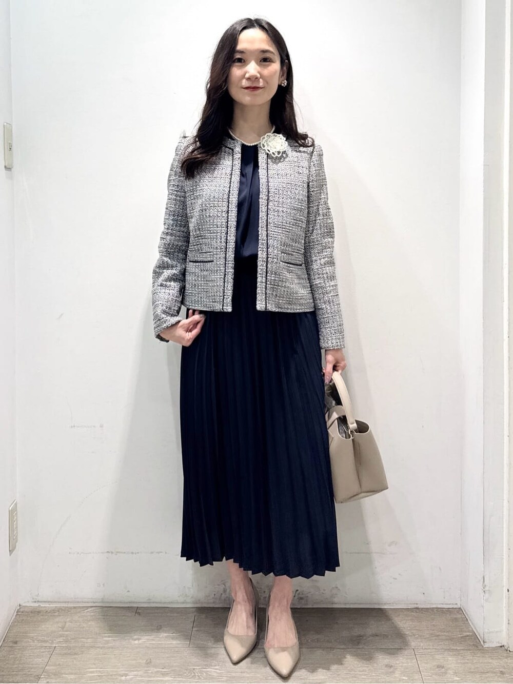 ブルー系のワンピース、ブラック系のノーカラージャケット、ベージュ系のハンドバッグを着用したレディースの春コーディネートの5枚目の写真