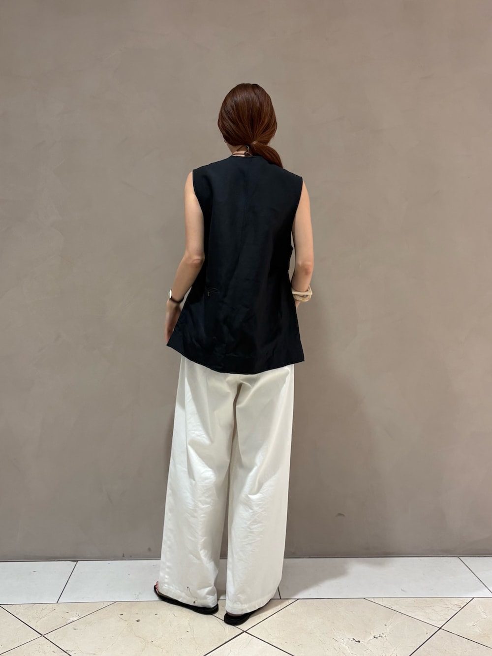 ホワイト系のその他パンツ、ブラック系のダウンベストを着用したレディースの春コーディネートの3枚目の写真