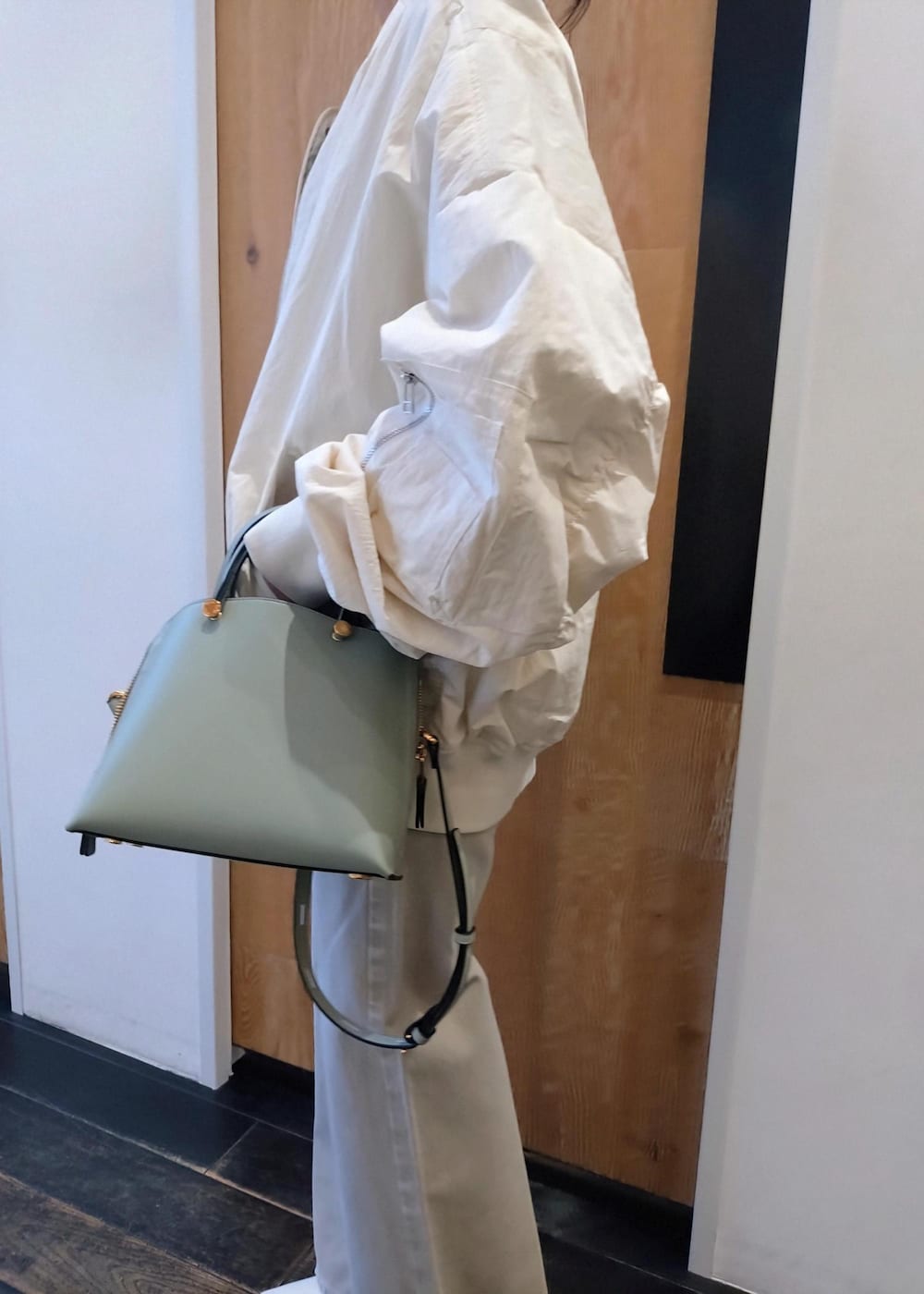 ホワイト系のパンプス、グリーン系のハンドバッグ、ホワイト系のMA-1を着用したレディースの冬コーディネートの8枚目の写真