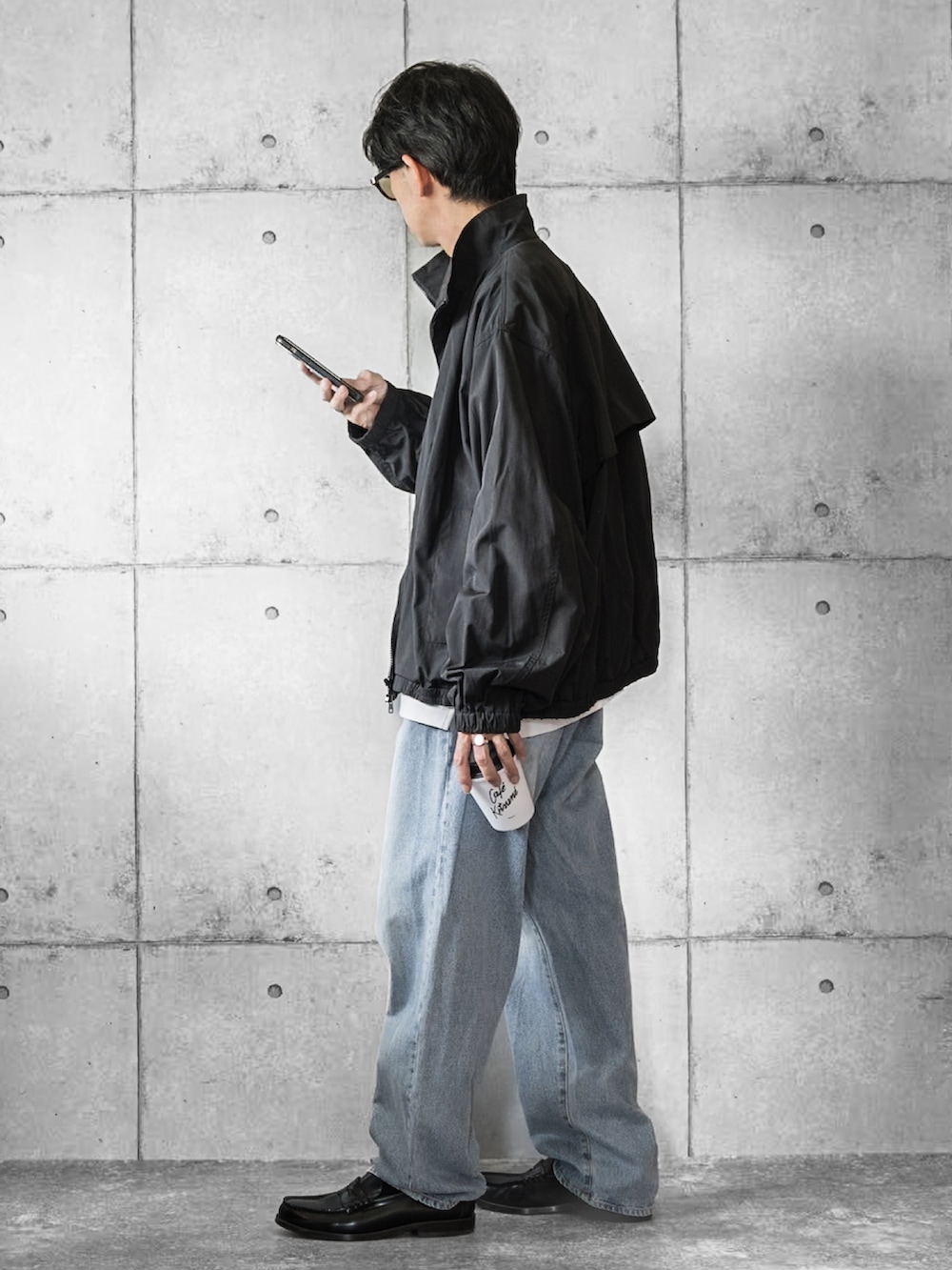 ブラック系のジャージ、ホワイト系のTシャツ/カットソー、ブルー系のデニムパンツを着用したメンズの秋コーディネートの2枚目の写真