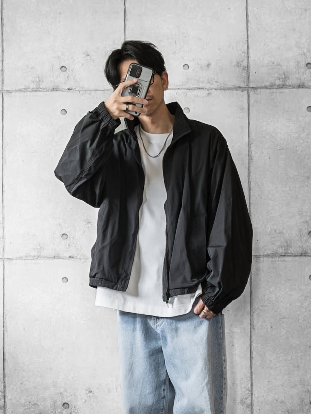 ブラック系のジャージ、ホワイト系のTシャツ/カットソー、ブルー系のデニムパンツを着用したメンズの秋コーディネートの3枚目の写真