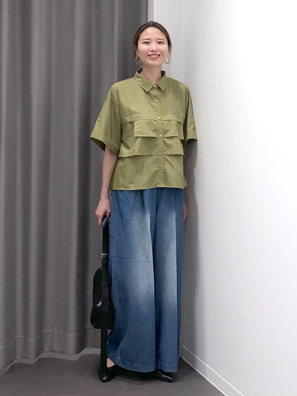 ブラック系のパンプス、ブラック系のショルダーバッグ、グリーン系のシャツ/ブラウスを着用したレディースの夏コーディネートの2枚目の写真