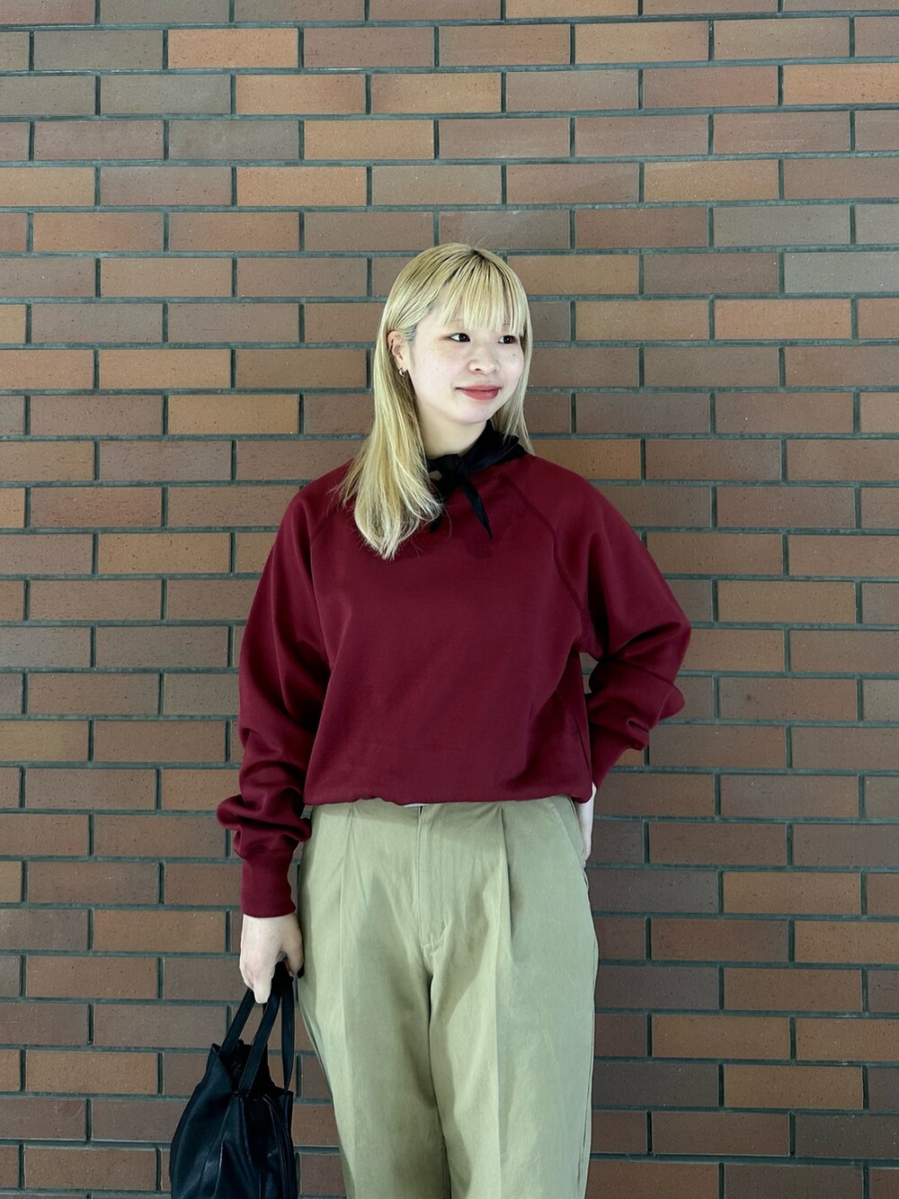 レッド系のスウェット、ベージュ系のその他パンツ、ブラック系のショルダーバッグを着用したレディースの冬コーディネートの5枚目の写真