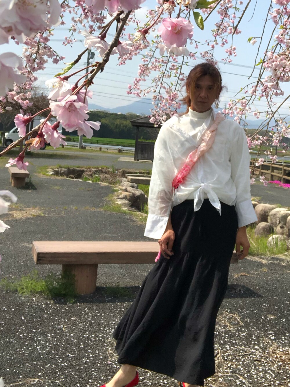 ブラック系のスカート、レッド系のパンプス、ホワイト系のトップスを着用したメンズの春コーディネートの5枚目の写真