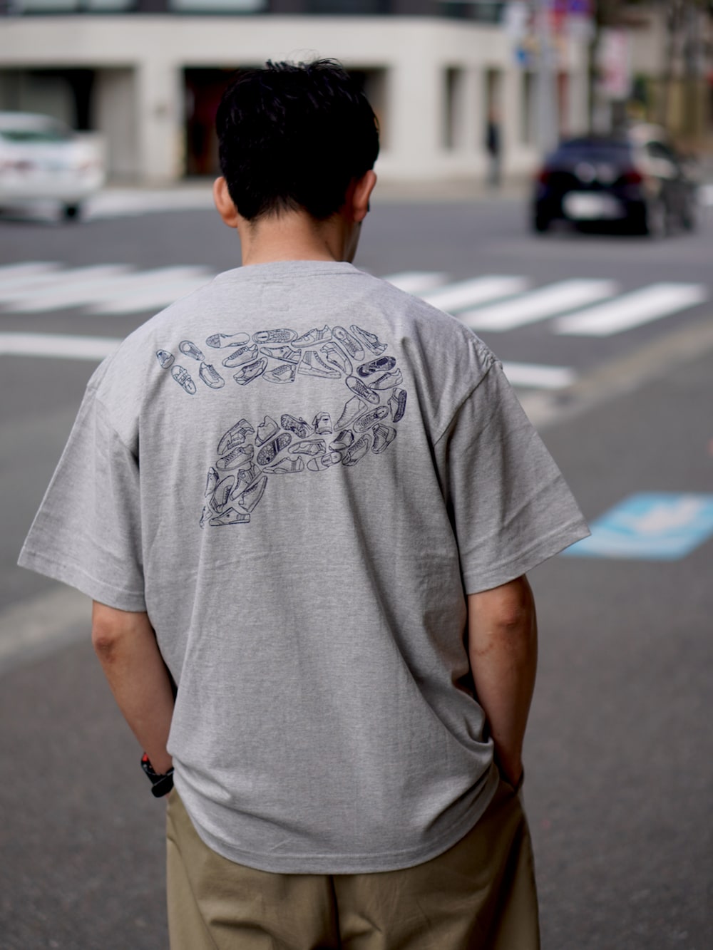 グレー系のTシャツ/カットソー、ベージュ系のチノパンツ、ブラック系のスニーカーを着用したメンズの春コーディネートの2枚目の写真