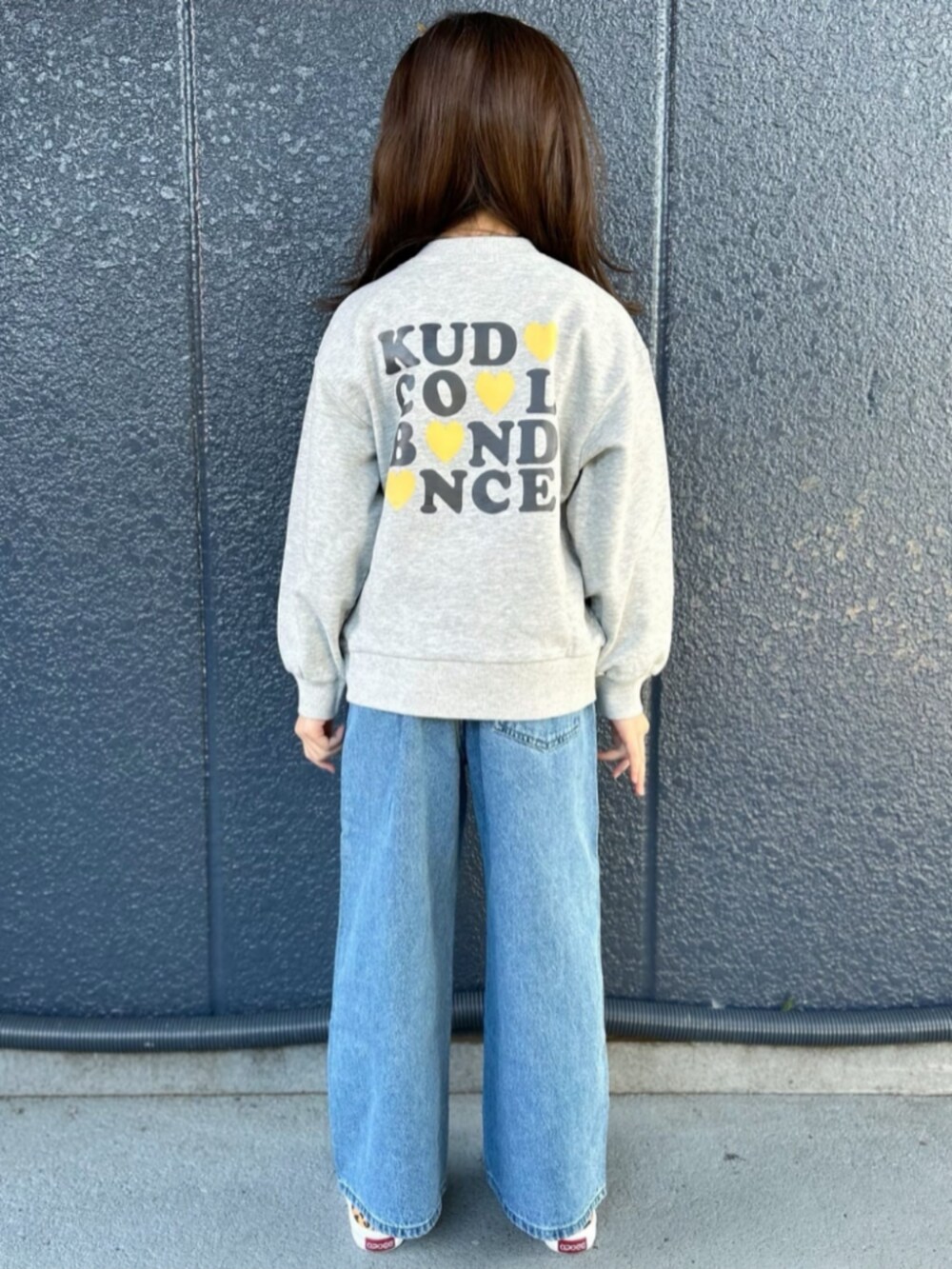グレー系のスウェット、ブルー系のデニムパンツ、ブラック系のショルダーバッグを着用したキッズの冬コーディネートの4枚目の写真