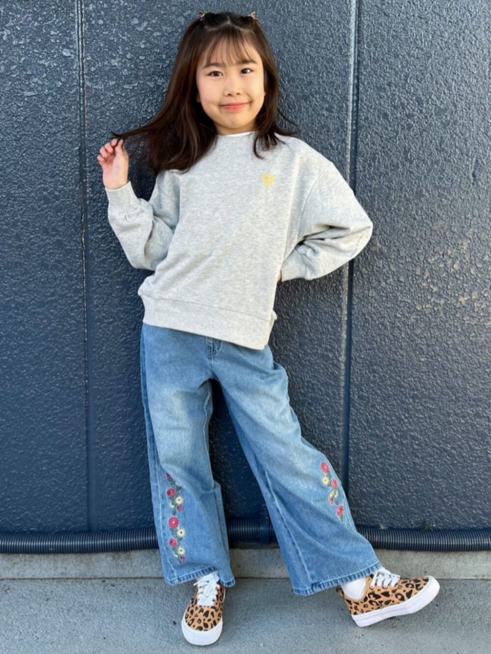グレー系のスウェット、ブルー系のデニムパンツ、ブラック系のショルダーバッグを着用したキッズの冬コーディネートの2枚目の写真