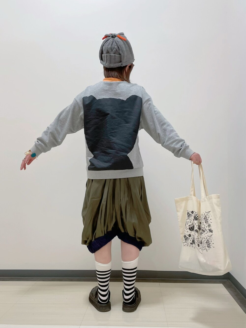 グレー系のスウェット、グリーン系のパンツ、ホワイト系のトートバッグを着用したレディースの春コーディネートの3枚目の写真