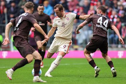 Bundesliga, 27. Spieltag – Samstag: Bayern Munich's English forward #09 Harry Kane (C) shoots past St Pauli's Belgian defender #44 Siebe van der Heyden (R) and St Pauli's Austrian defender #04 David Nemeth during the German first division Bundesliga football match between FC Bayern Munich and St Pauli in Munich, southern Germany on March 29, 2025.