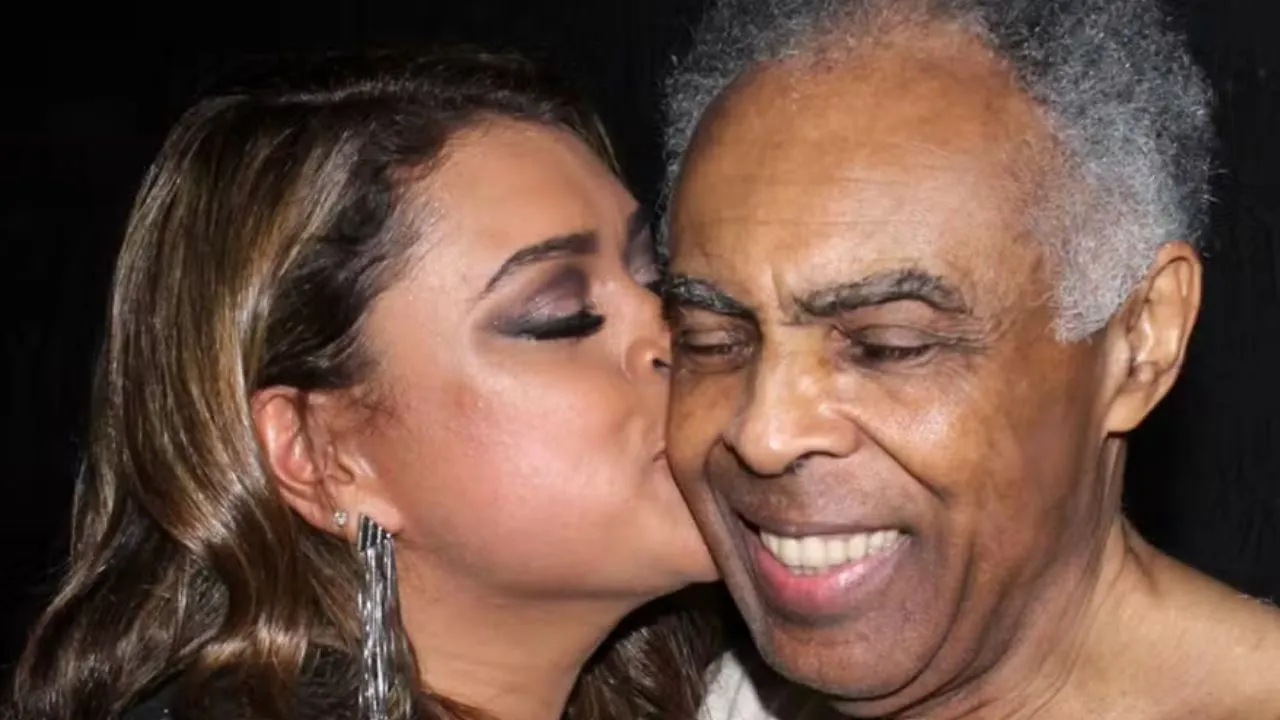 Preta Gil, de olhos fechados, dá um beijo na bochecha direta do pai, que sorri