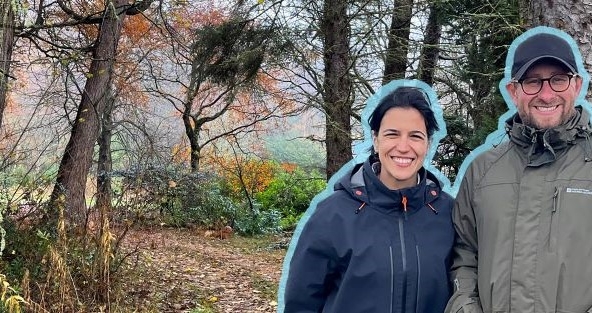 Couple in the woods smiling on a gloomy cold day