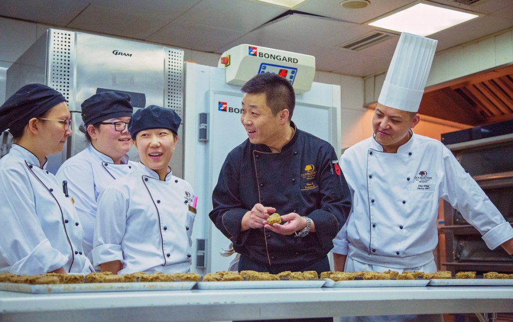Chefs laughing in a kitchen as they prepare biscuits