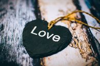 Home Close-up of a heart-shaped slate inscribed with 'Love' on a rustic wooden background, ideal for Valentine's themes.
