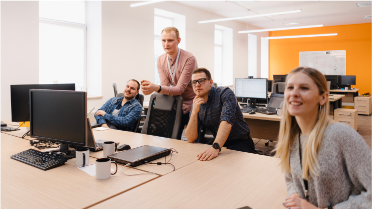 Colleagues in an office observing a computer screen.