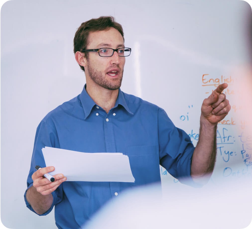 An educator holding notes while presenting in front of a class.