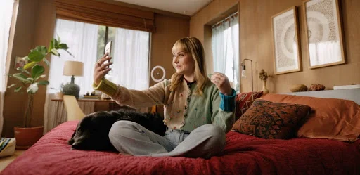 Blind woman with blonde hair wearing a colorful cardigan, holding a Pixel phone for a selfie