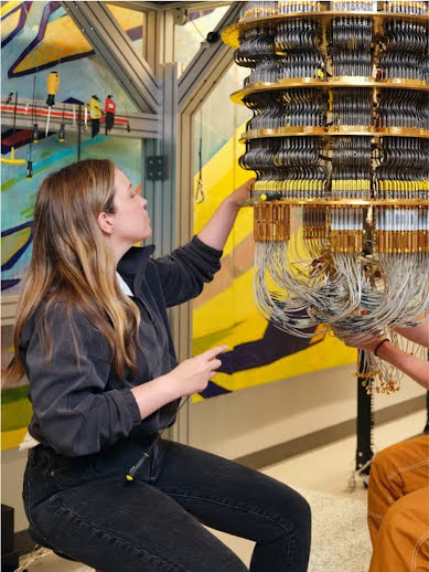 Una mujer trabaja en una computadora cuántica en un laboratorio y acomoda el cableado complejo.