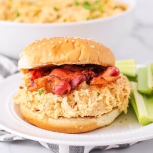 Slow Cooker Crack chicken served on a bun topped with bacon.