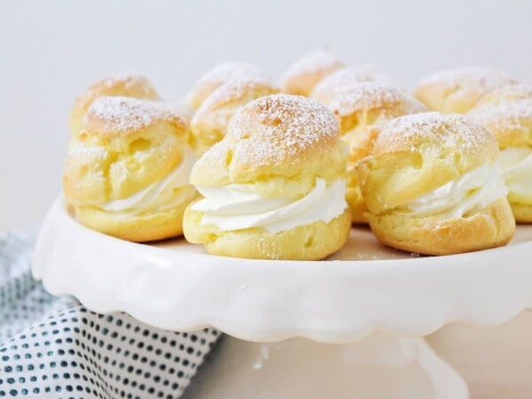 Homemade Cream Puffs on white cake stand.