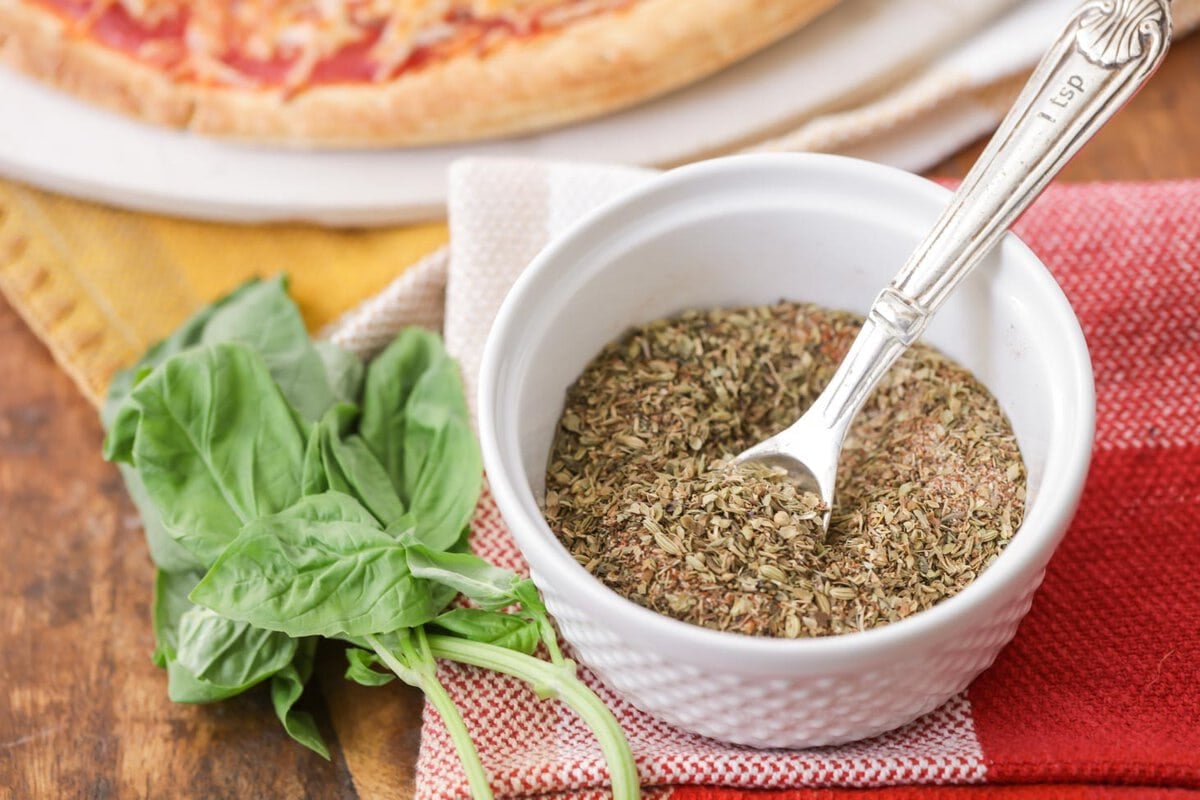 If you make homemade pizza, you NEED this easy pizza seasoning. It's the perfect ratio of seasonings and herbs for a tasty pizza every time! A white bowl of pizza seasonings.