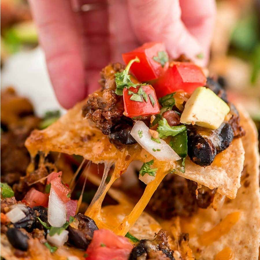 This piled-high loaded nachos recipe is the perfect game-day food or appetizer -customize it with your favorite toppings! Loaded Nachos recipe topped with cheese and pico de gallo.