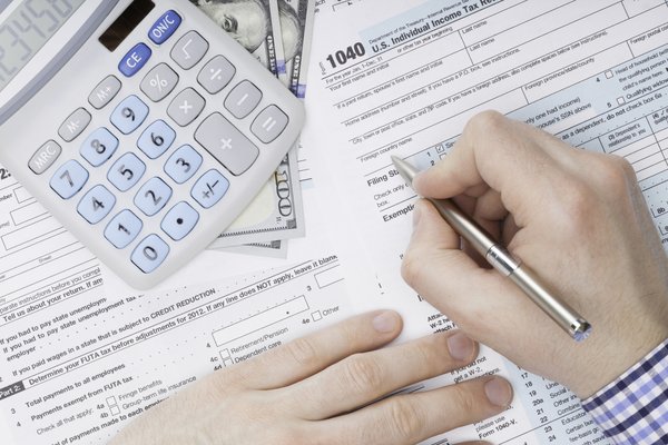 Hands holding a pen and filling out IRS documents.