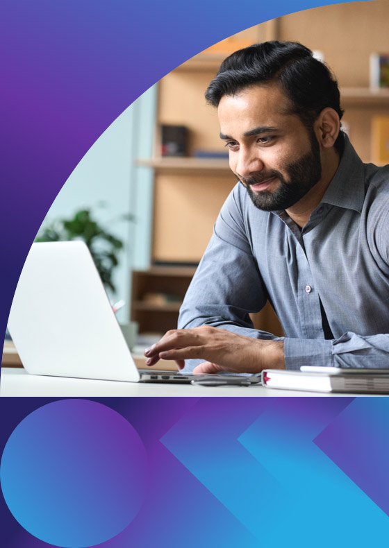 man smiling and looking through his laptop